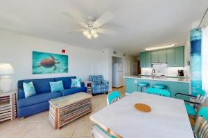a living room with a blue couch and a table at Tradewinds 601 in Orange Beach