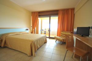 a bedroom with a bed and a desk and a television at Eden Residence Club in Torre Ovo