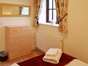 a bedroom with a bed and a dresser and a window at The Stable in High Halstow