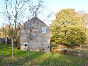 an old stone house in a field with trees at Heckberry Cottage in Burtree Ford