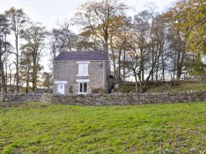 Heckberry Cottage في Burtree Ford: منزل حجري في حقل مع جدار حجري