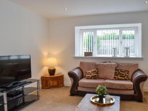 a living room with a couch and a flat screen tv at Kirroughtree Steading 1 - Uk5859 in Newton Stewart