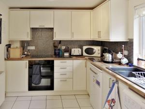 a kitchen with white cabinets and a sink at Shore Cottage in Rockfield