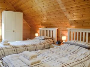 2 letti in una camera con soffitti in legno di Quarry Lodge a Little Marcle