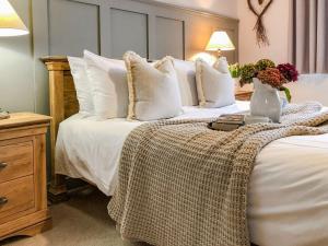 Una cama con almohadas blancas y un jarrón con flores. en Maes Y Bryn Farmhouse en Llanwrda