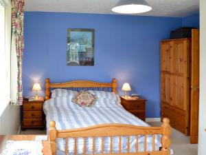 a bedroom with a wooden bed with a blue wall at Tregoona in Crantock
