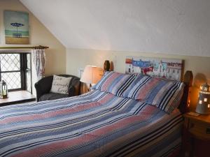 a bedroom with a bed with a striped blanket and a chair at The Studio Cottage in Cemaes Bay