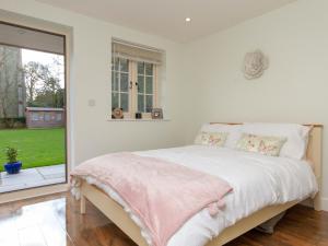 a white bedroom with a bed and a window at Breckland Cottage in Hockwold cum Wilton