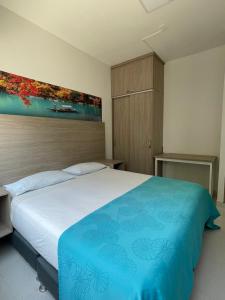 ein Schlafzimmer mit einem großen Bett mit einer blauen Decke in der Unterkunft HOTEL G22 COLECTION in Florencia