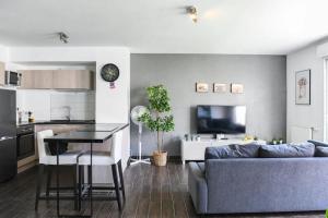 uma sala de estar com um sofá azul e uma cozinha em Le Capé-Grand appartement avec terrasse et jacuzzi em Marselha