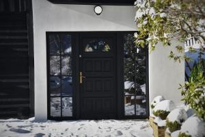 a black front door with snow on the ground at Oto Widoki in Szklarska Poręba