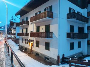 een wit gebouw met balkons in de sneeuw bij APPARTAMENTO STELLA ALPINA in Cortina dʼAmpezzo