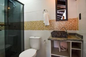 a bathroom with a toilet and a sink and a mirror at Estúdio com Varanda e Churrasqueira no Campeche P2013 in Florianópolis