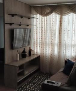 Cette chambre comprend un lit, une télévision et une fenêtre. dans l'établissement Apartamento encantandor-perto centro e shopping, à Poços de Caldas