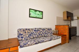 un sofá en una habitación con TV en la pared en Meia quadra da Praia nos Ingleses, 4 hóspedes P2057, en Florianópolis