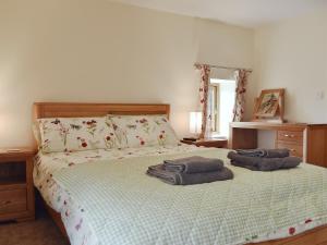 1 dormitorio con 1 cama con 2 toallas en South Barn, en Monk Okehampton