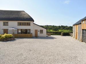a white house with a thatched roof and a gravel driveway at South Barn in Monk Okehampton