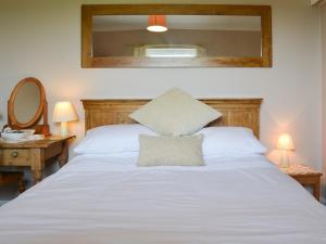 a bedroom with a white bed with a mirror at Jasmine Cottage in Knitsley