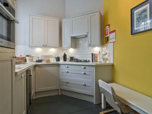 a kitchen with white cabinets and a yellow wall at Coastguard Retreat in Ramsgate