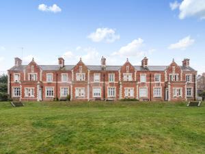 a large red brick building with a grass field in front at Coastguard Retreat in Ramsgate