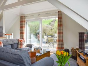 uma sala de estar com um sofá e uma porta de vidro deslizante em Camellia Cottage em Saint Ewe
