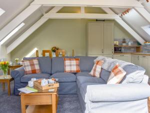 a living room with a blue couch in a attic at Camellia Cottage in Saint Ewe