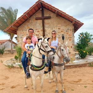 a family riding on horses in front of a church at Chalé bons ventos in Serra de São Bento
