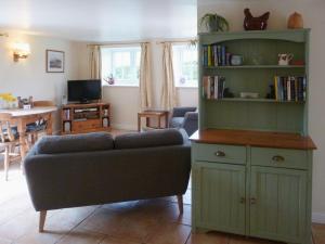 a living room with a couch and a book shelf at Wren Cottage in Netherbury