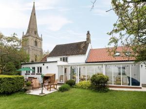 a white house with a church in the background at Church Cottage in Islip