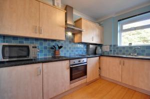 a kitchen with wooden cabinets and a microwave and a window at Mauve in Poole