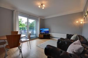 a living room with a couch and a table and a television at Mauve in Poole