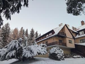 a building covered in snow with trees in front of it at DW Agat in Karpacz