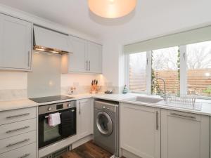 a kitchen with white cabinets and a sink and a dishwasher at Castle View Annex in Wareham