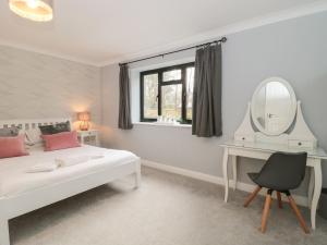 een slaapkamer met een bed, een spiegel en een bureau bij Castle View Annex in Wareham