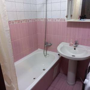 ein rosafarbenes Badezimmer mit einem Waschbecken, einer Badewanne und einer Badewanne in der Unterkunft 1к квартира Антоновича. Олімпійська in Kiew
