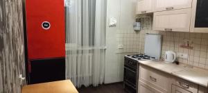 uma pequena cozinha com um fogão e uma porta vermelha em 1к квартира Антоновича. Олімпійська em Kiev