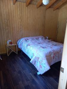 a bedroom with a bed in a wooden room at Cabaña Los Chilcos in Curacautín