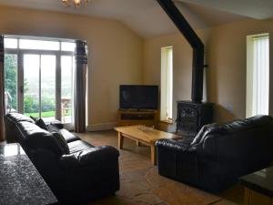 a living room with black leather furniture and a wood stove at Durham Cottage-27765 in Wolsingham