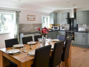 a kitchen with a wooden table with chairs and a dining room at East Croft Barn in Halwill