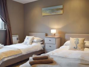 ein Schlafzimmer mit 2 Betten und einem Tisch mit einer Lampe in der Unterkunft Gower Sunset Views in Llanelli
