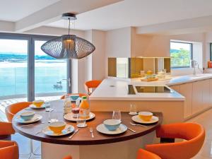 a kitchen with a table with orange chairs and a kitchen with a island at Tan Y Fford in Bangor