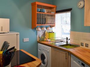 a kitchen with a washing machine and a sink at Parsley Cottage in Tideswell