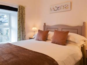 Un dormitorio con una cama blanca con almohadas y una ventana en Parsley Cottage, en Tideswell