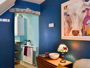 a blue room with a painting of a cow on the wall at Parsley Cottage in Tideswell