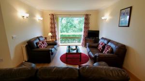 a living room with leather furniture and a large window at Allt Beag in Lochearnhead