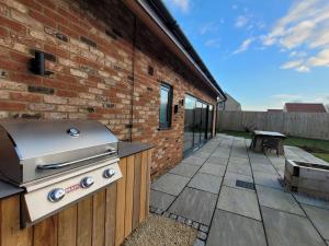 a grill on a patio next to a brick building at Castle Hill Barn, Ashlin Farm Barns in Lincoln