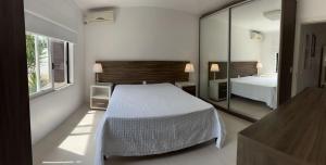 une chambre avec un lit blanc et un miroir dans l'établissement Casa com piscina Praia dos Molhes, à Torres 38 autres photos