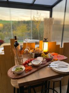 un tavolo in legno con cibo e una bottiglia di vino di Cabane au style scandinave et son bain nordique a Bouillon