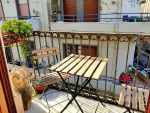 un banco de madera y una mesa en el balcón en Bellini Apartment en Catania