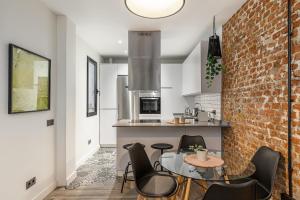 uma cozinha com uma parede de tijolos e uma mesa e cadeiras em BNBHolder Cool Atocha Station em Madri